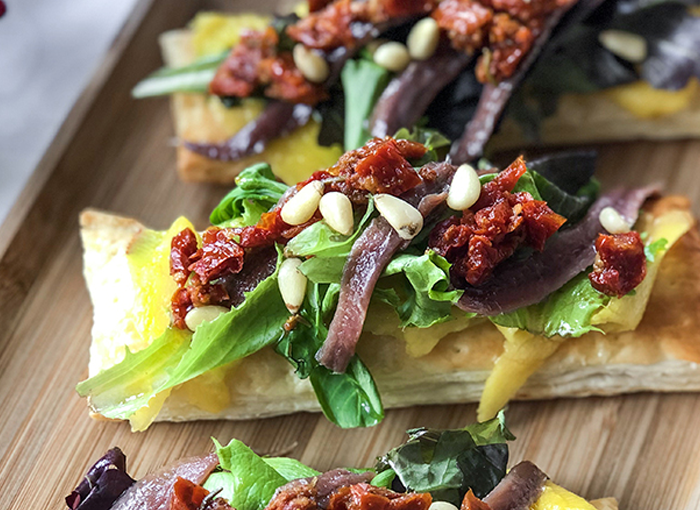 Hojaldre de mango, anchoas, piñones y tomate.