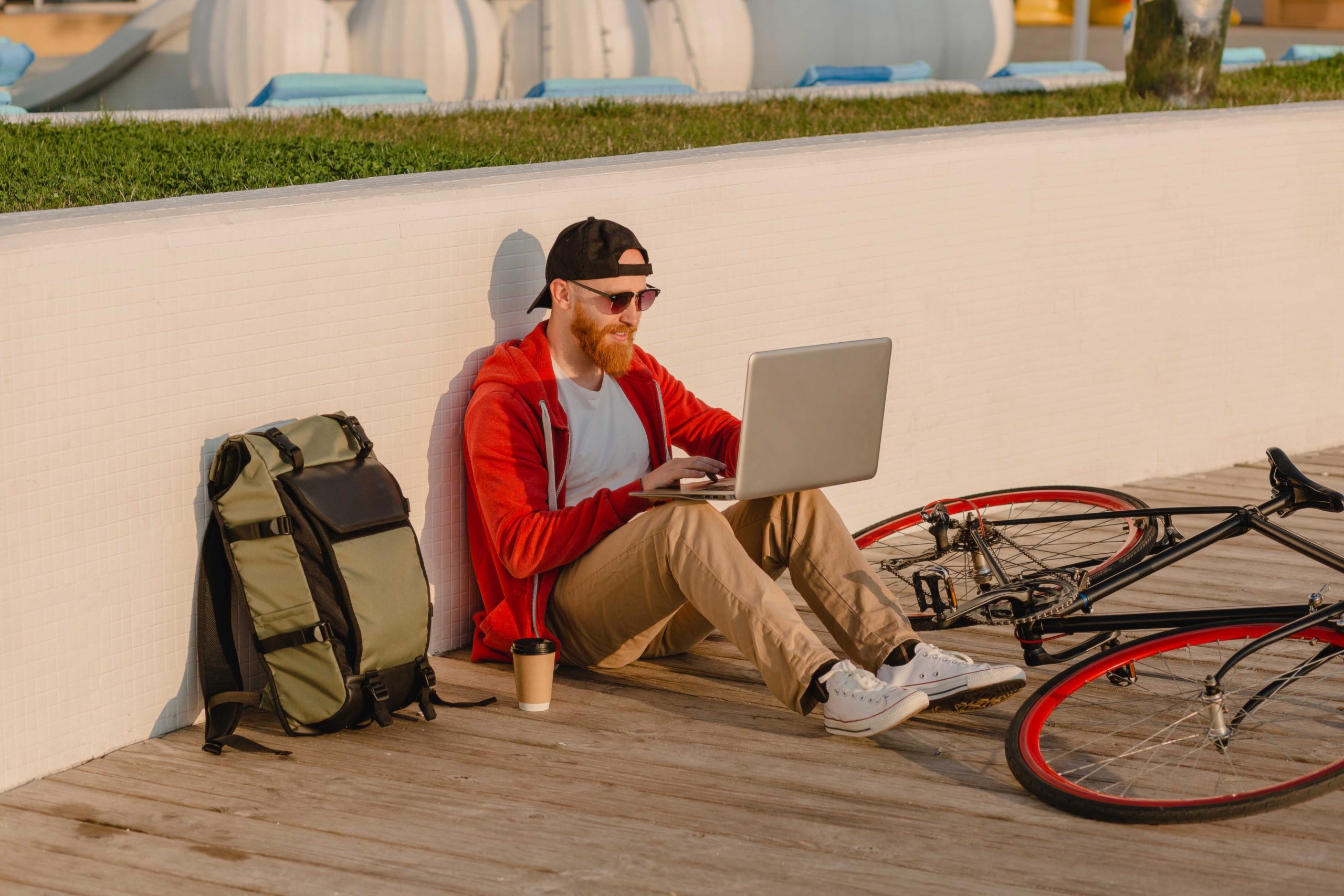1622542137 handsome shipster style bearded man working online freelancer on laptop with backpack and bicycle in morning sunrise by the sea healthy active lifestyle traveler backpacker scaled Moncloa