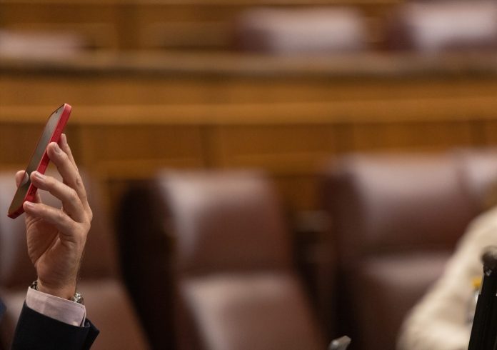 Un diputado con su móvil durante una sesión plenaria en el Congreso de los Diputados, a 14 de diciembre de 2022, en Madrid (España).