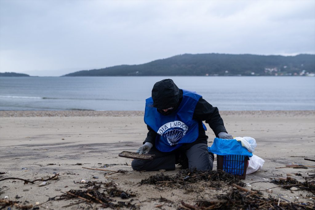 Un voluntario recoge pellets en las playas gallegas.