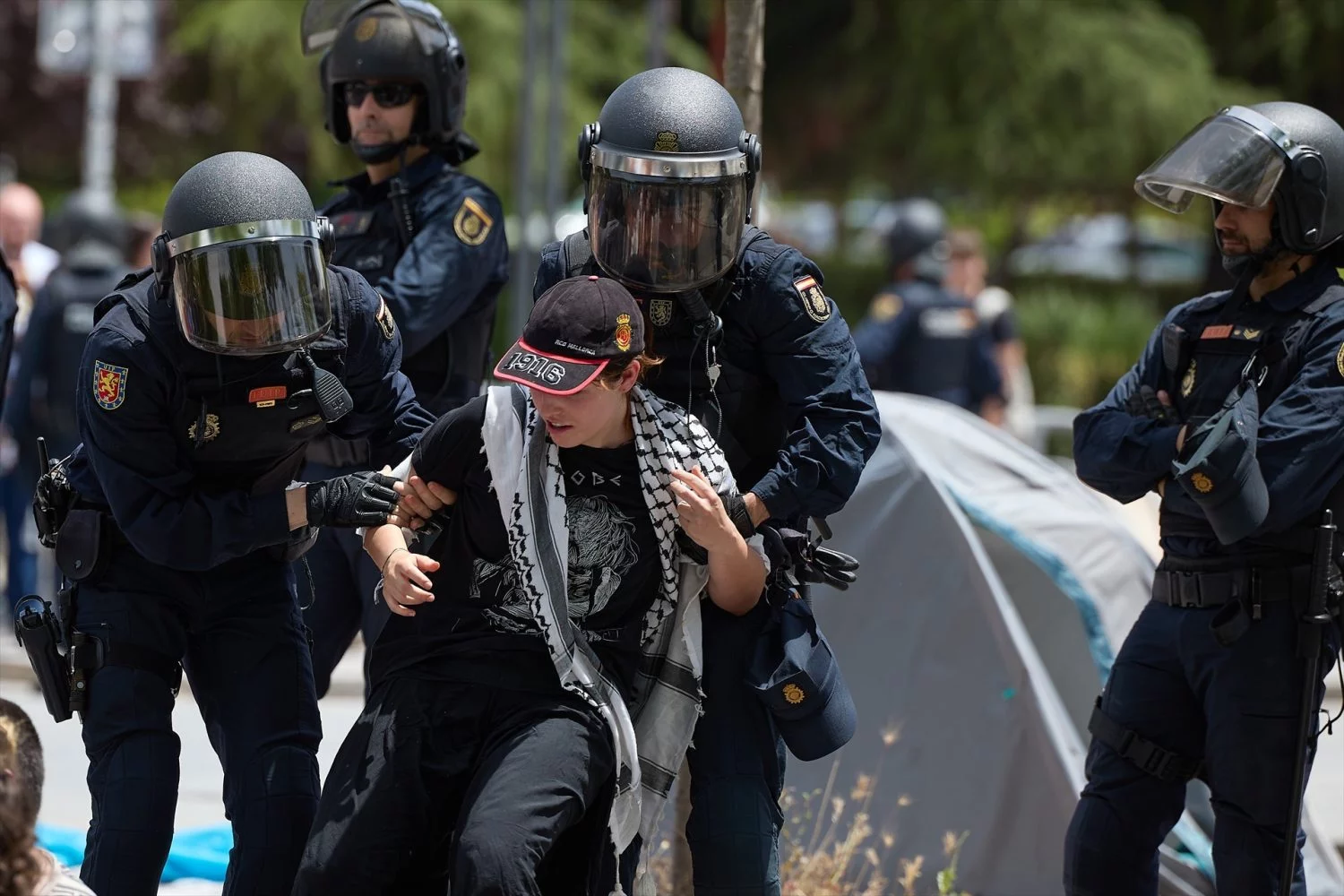 Varios agentes de Policía Nacional se llevan a un hombre durante una manifestación de los estudiantes acampados en la Universidad Complutense de Madrid (UCM)