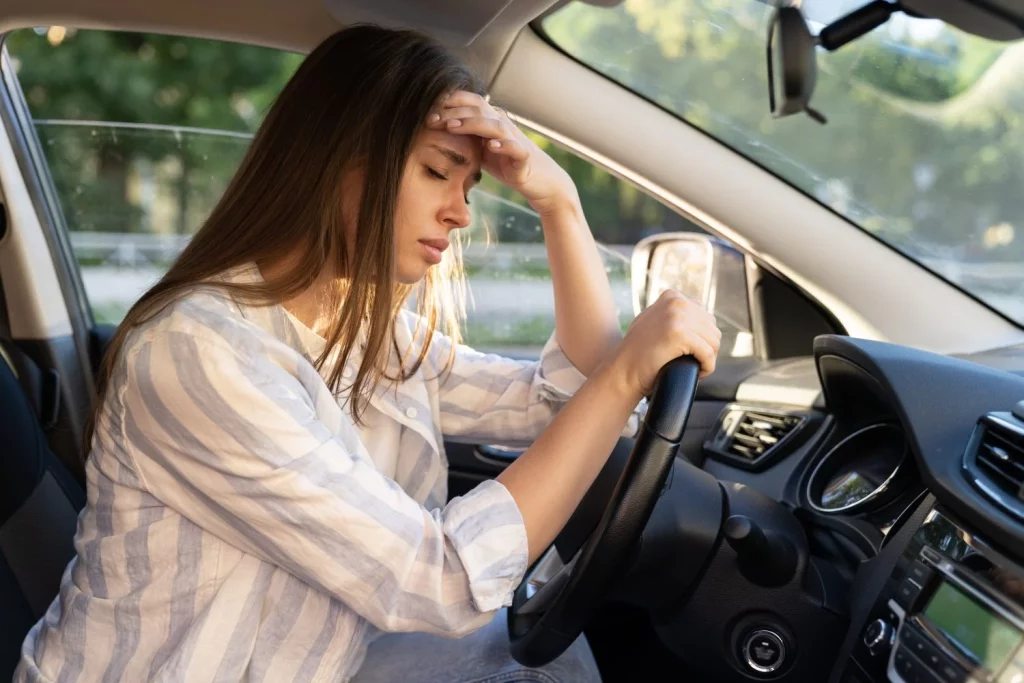 tired young woman car driver suffer from headache migraine pain inside vehicle touch forehead Moncloa