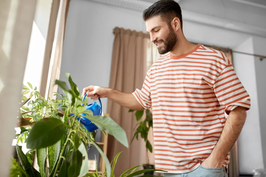 hombre feliz sonriente regando flores en casa Moncloa