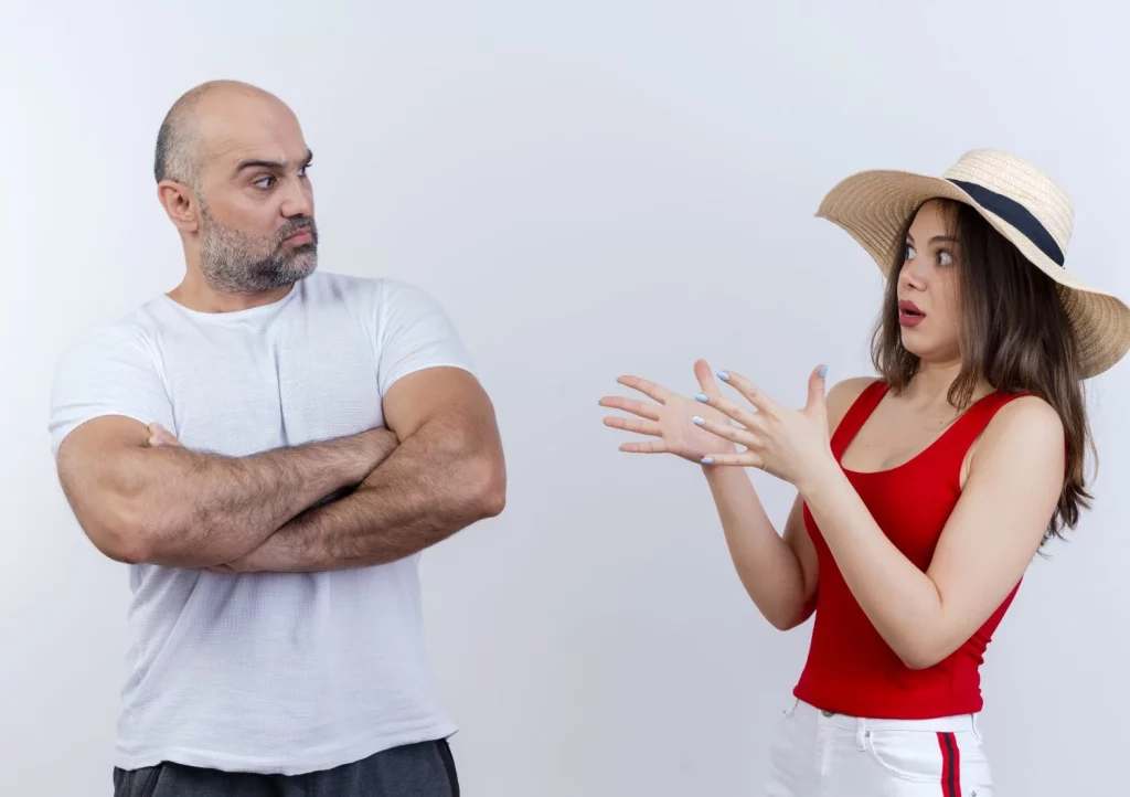 Calor y violencia: ¿Cómo los episodios de calor afectan a nuestro comportamiento y desatan conflictos? 4 Moncloa pareja adulta hombre de pie con el ceno fruncido con postura cerrada y mujer impresionada con sombrero extendiendo las manos ambos mirando el uno al otro Moncloa